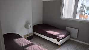 A small, single-bed room with a window, a bedside table with a lamp, and a radiator. - T4 center LOURDES and near sanctuaries (Lourdes)