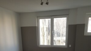 A room with two beds, a small table, a TV, and a window with a view of trees. - T4 center LOURDES and near sanctuaries (Lourdes)