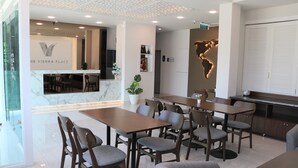 Un moderno hall de hotel con un mostrador de recepción de mármol, varias zonas de estar y una pared decorativa con un mapa.