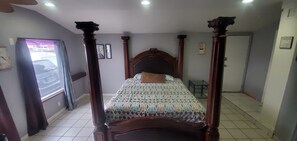 Relax in a cozy space with a four-poster bed and a comfortable chair.