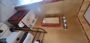 Bathroom features a sink, mirror, and shelf with toiletries.