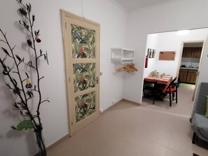 A room with a dining table, chairs, a hanging coat rack, and a door with a decorative panel. - Cozy Central II Comfortable, welcoming Studio (Ponta Delgada)
