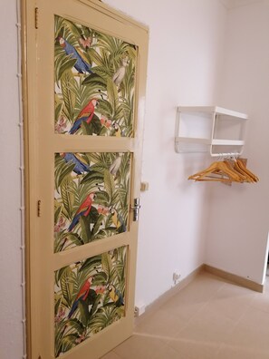 A door with a tropical bird mural, a white shelf, and a tiled floor. - Cozy Central II Comfortable, welcoming Studio (Ponta Delgada)