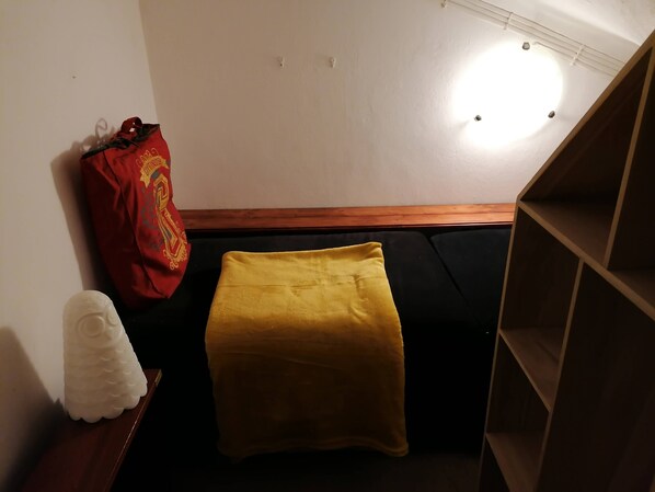 A room with a black sofa, a yellow throw blanket, a white decorative item, and a red bag with a logo. - Cozy Central II Comfortable, welcoming Studio (Ponta Delgada)