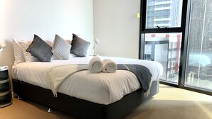 Una moderna camera d'hotel con un letto grande, una lampada da comodino e vista sulla città attraverso una grande finestra.