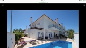 A two-story house with a swimming pool, a covered patio, and a satellite dish.