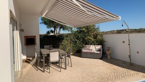 A covered patio with a table and chairs, a pool, and a view of the surrounding landscape.