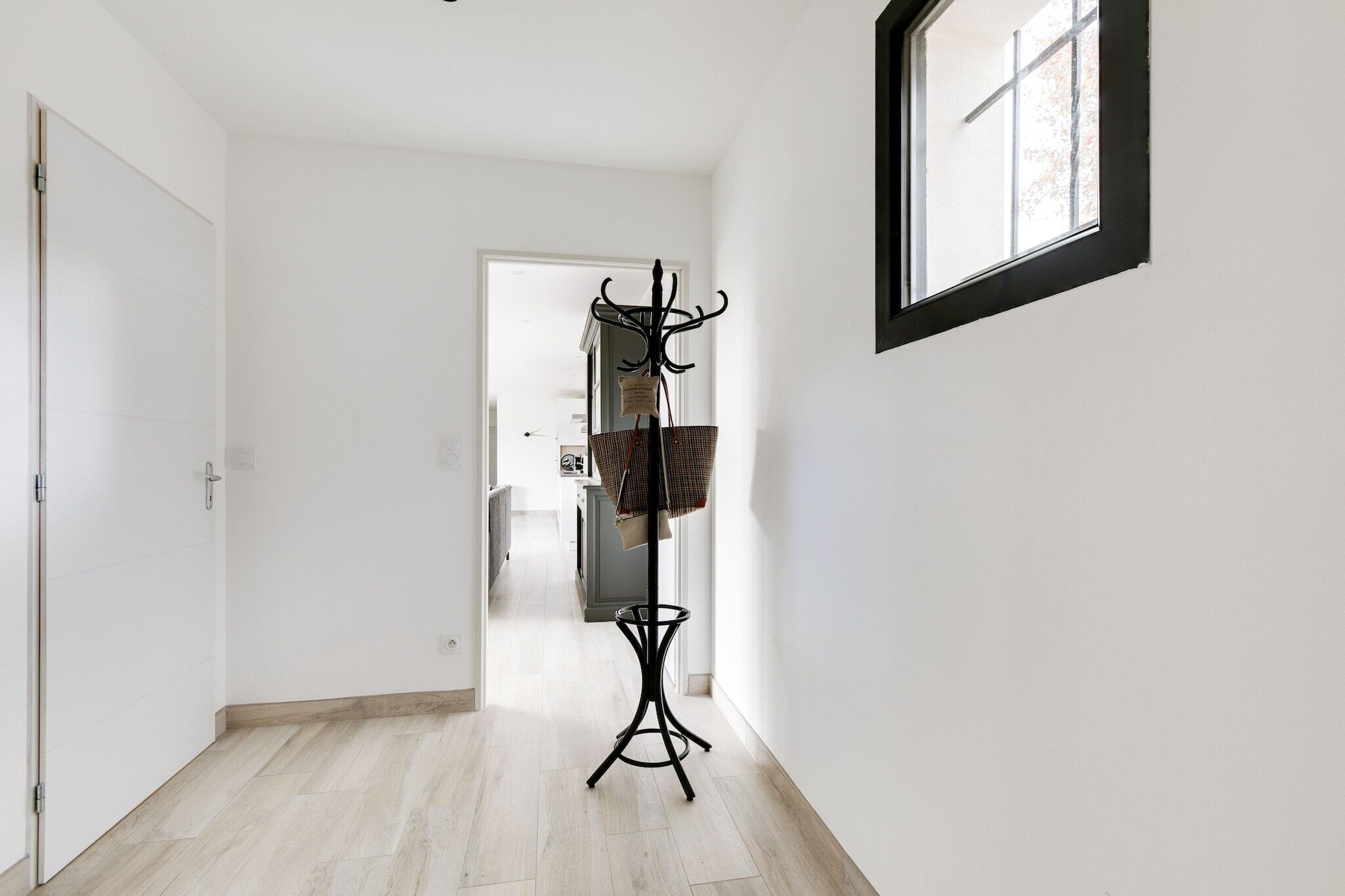 A hallway with a coat rack, a door, and a window.