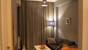 Een woonkamer met een bank, een salontafel, een lamp en een televisie.