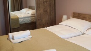 Een hotelkamer met een houten bedframe, een grote spiegel en net opgemaakte bedden.
