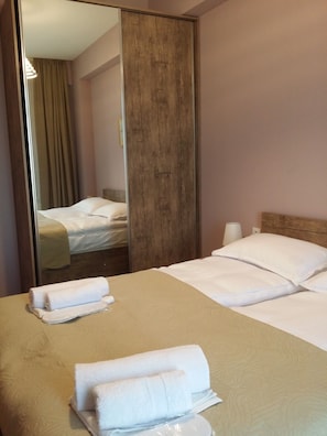 A hotel room with a wooden bed frame, a large mirror, and neatly made beds. - cozy new stylish Tbilisi view apartment -self check in free Wi-fi (Vake-Saburtalo)
