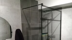 Un bagno moderno con doccia vetrata, lavandino bianco e un piccolo sgabello.