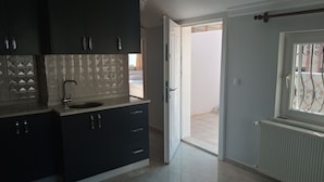 A modern kitchen with dark cabinets, a sink, and patterned backsplash. - Bulut Apartment (Konyaalti)