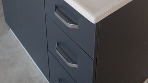 A kitchen with a stainless steel sink, a white countertop, and dark cabinets. - Bulut Apartment (Konyaalti)