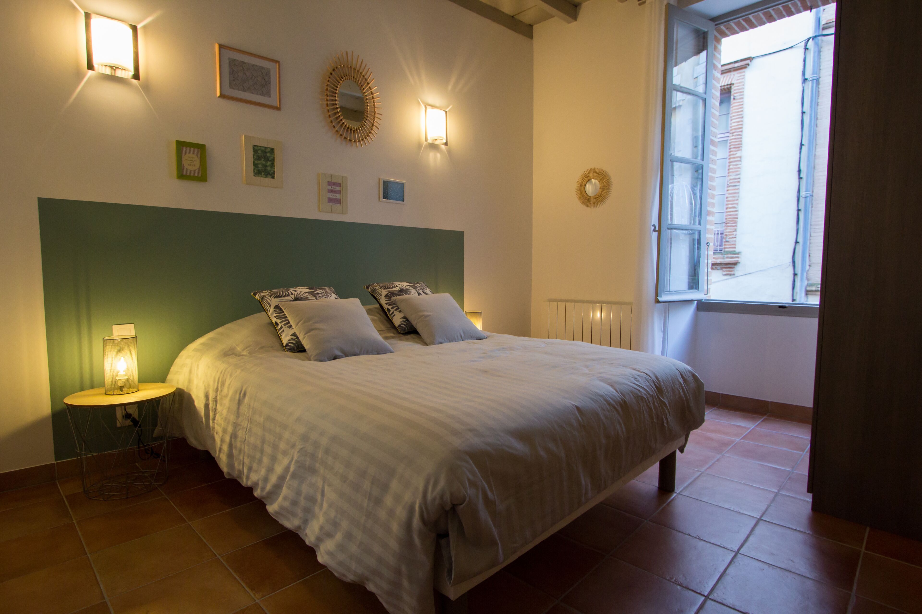 Un dormitorio con cama, lámparas de noche, ventana y adornos en la pared.