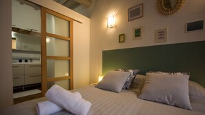 A hotel room with a bed, a nightstand, a mirror, and a view of the kitchen. - In complete privacy in the historic center (Montauban)