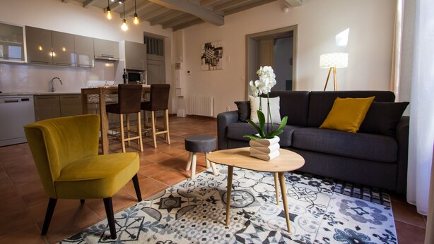 A modern living room with a sofa, a yellow chair, a coffee table, and a patterned rug. - In complete privacy in the historic center (Montauban)