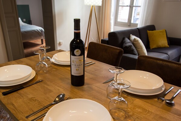 A dining table set with plates, cutlery, wine glasses, and a bottle of wine.