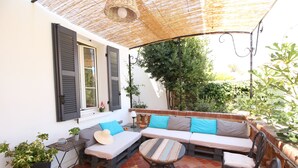 Un patio con un sofá, sillas, una mesa y una planta en maceta.