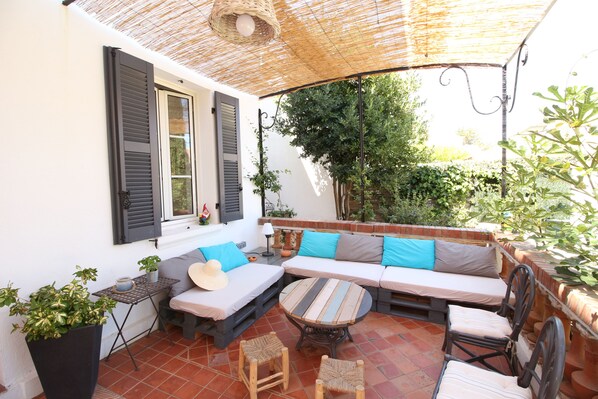Une terrasse avec un canapé, des chaises, une table et une plante en pot.