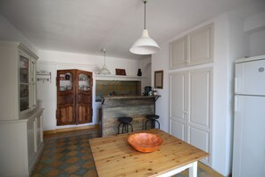 Une cuisine avec une table en bois, un luminaire suspendu et un réfrigérateur.