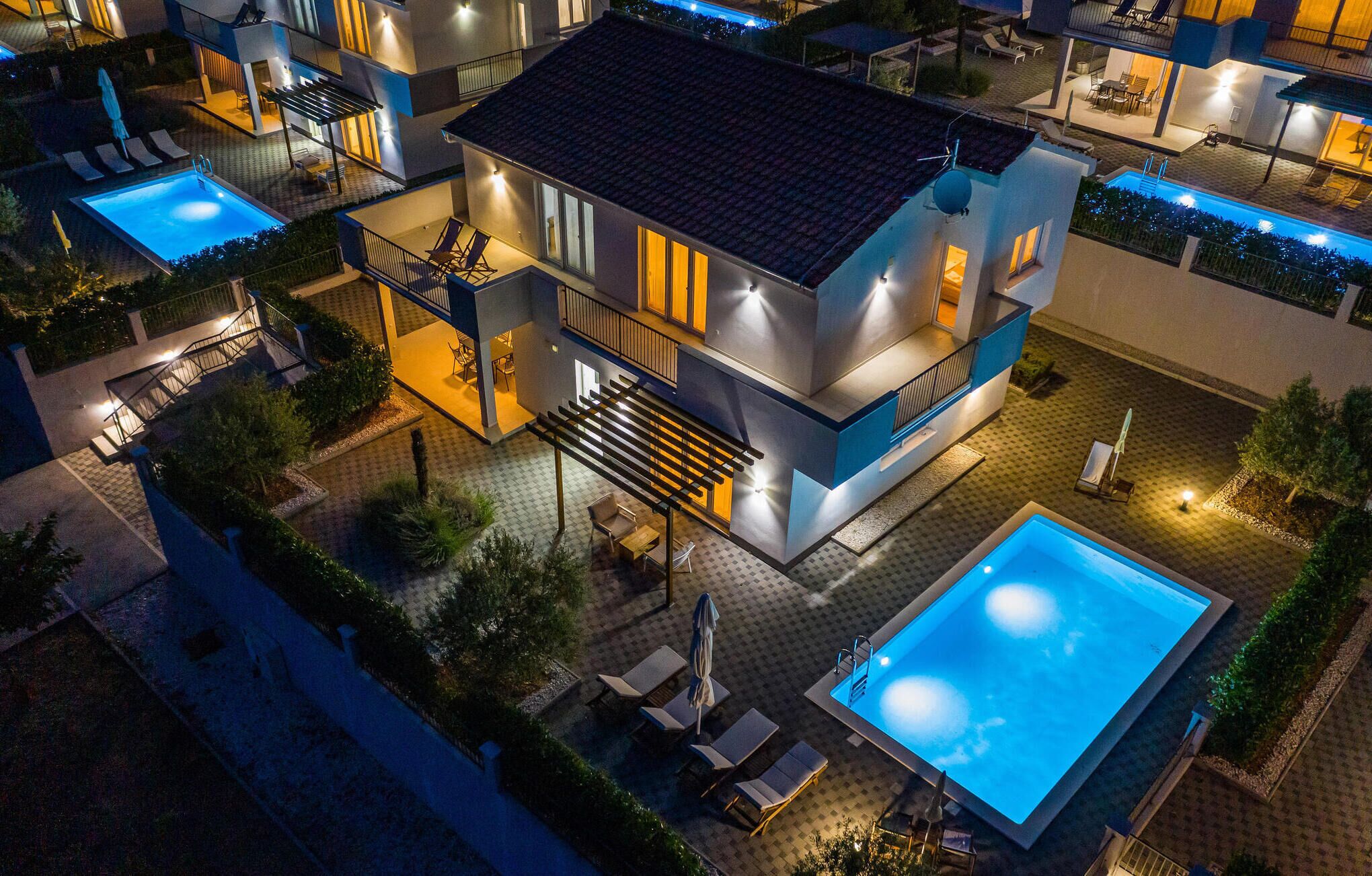 Un edificio moderno de varios pisos con piscina en la azotea, zona de estar al aire libre y patio bien iluminado.