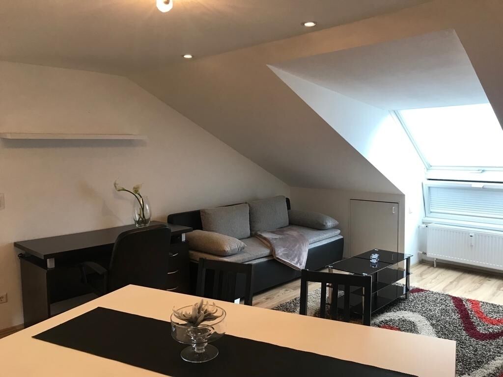 Eine moderne Loftswohnung mit Essbereich, einer Couch und Blick zum Himmel durch ein Dachfenster.