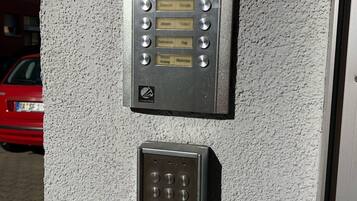 A wall-mounted intercom system with a keypad and a doorbell.