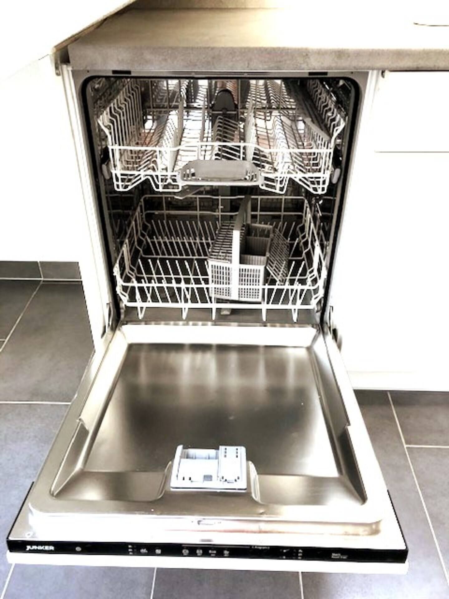 An open dishwasher with multiple racks and a control panel.
