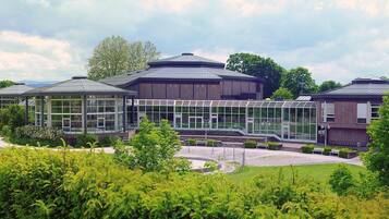 Ein modernes Gebäude mit Glasfassade, einem zentralen Atrium und einer Statue im Vordergrund.