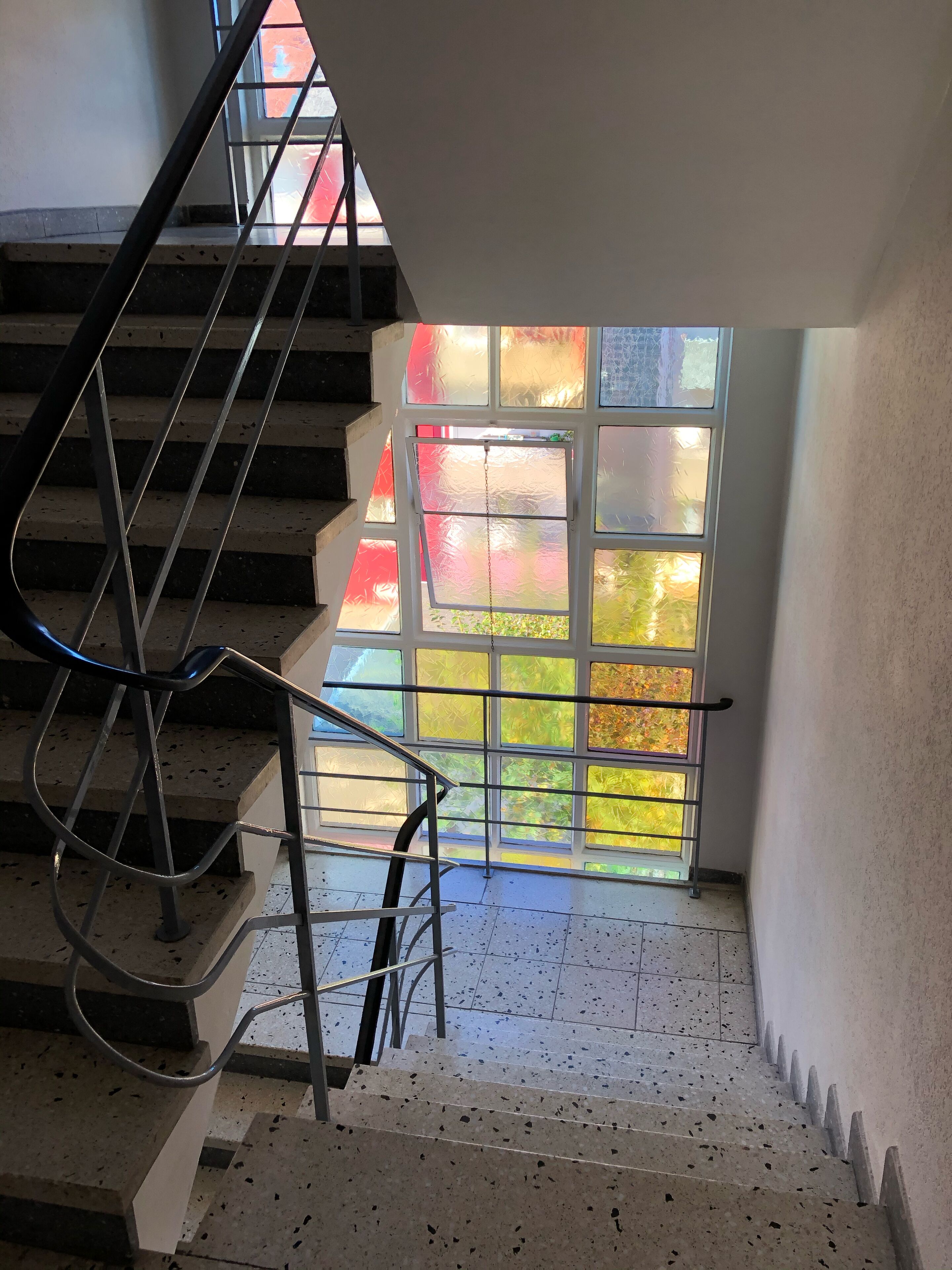 Un escalier avec des rampes en métal menant à une porte dont les panneaux sont en verre dépoli.