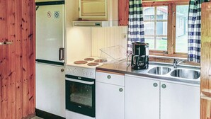 A compact kitchen with a refrigerator, stove, oven, and a coffee maker on the counter.