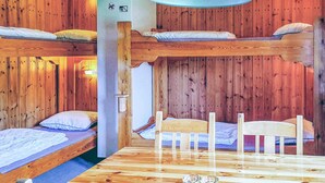 A cabin-style room with bunk beds, a wooden dining table, and a wooden wall.