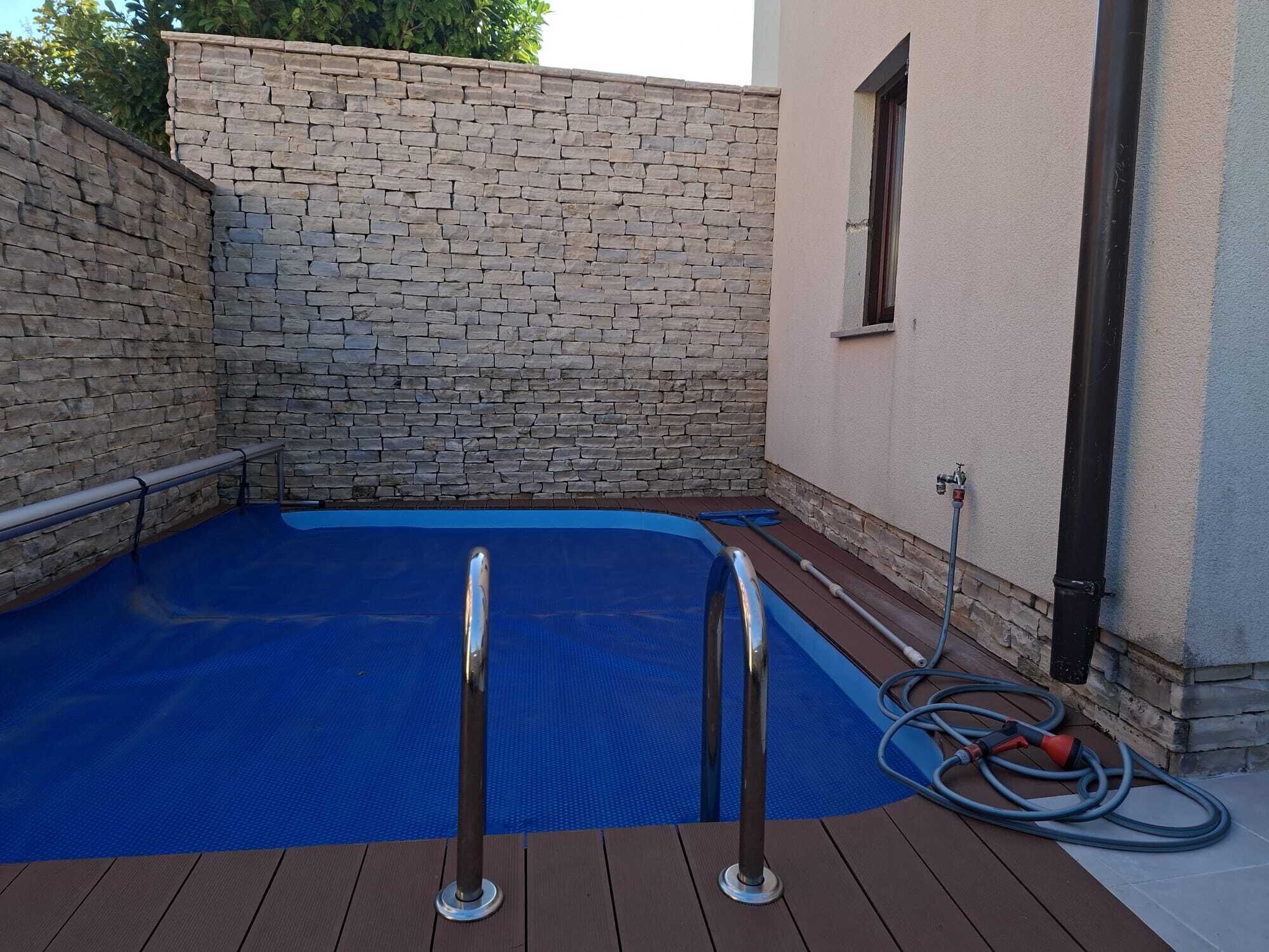 A swimming pool with a stone wall and a wooden deck.