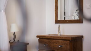 Een houten dressoir met een spiegel, een lamp en een bed in een hotelkamer.