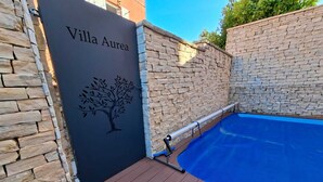 Een zwembadgedeelte met een stenen muur en een bord waarop 'Villa Aurea' staat.