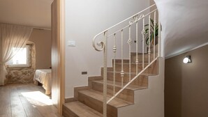 Una escala amb graons de fusta i barana blanca que condueix a un aterri amb una planta en test.