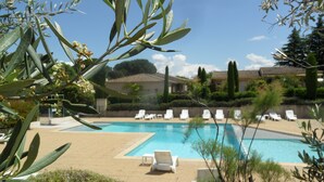 A pool area with lounge chairs and a building in the background. - A Mazet at the foot of the Alpilles (2 stars) (Saint-Rémy-de-Provence)