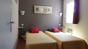 A hotel room with two beds, a wall-mounted shelf with a framed picture, and a window with curtains. - A Mazet at the foot of the Alpilles (2 stars) (Saint-Rémy-de-Provence)