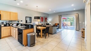 A modern kitchen with wooden cabinets, a black countertop, and a dining area with a table and chairs.