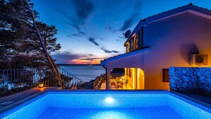 A modern house with a swimming pool, a stone wall, and a view of the sea at sunset. - Beach front home in Novigrad (Novigrad)