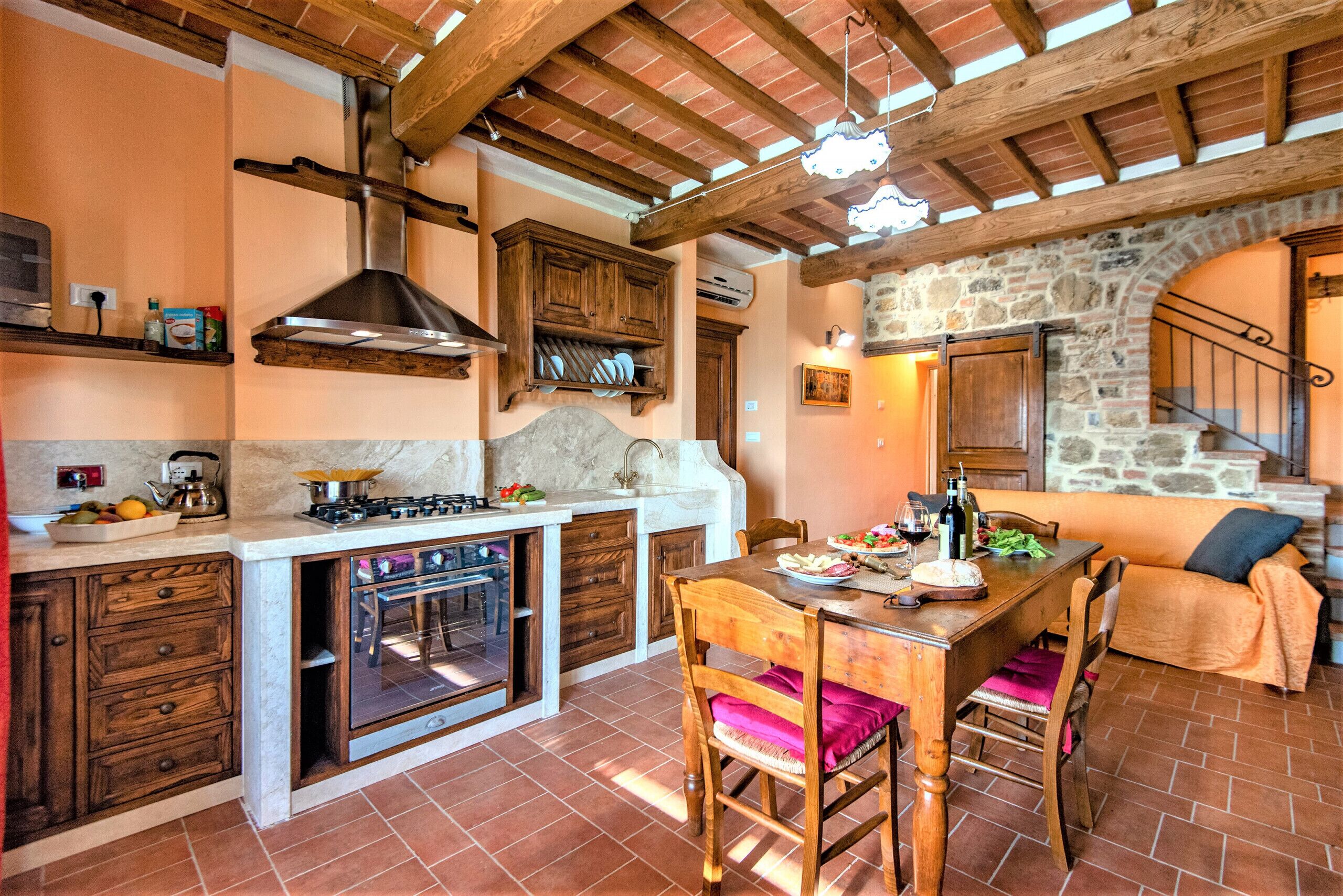 A kitchen with a built-in oven, wooden cabinets, and a stone wall.