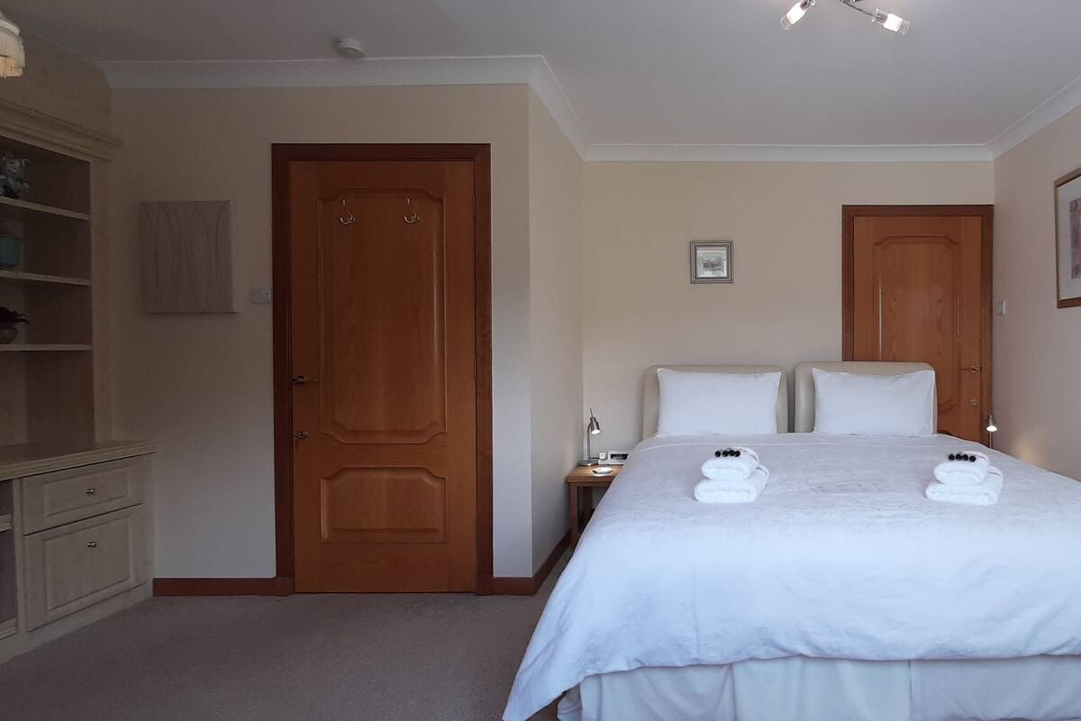 A hotel room with a large bed, two bedside tables, a wardrobe, and a mirror.