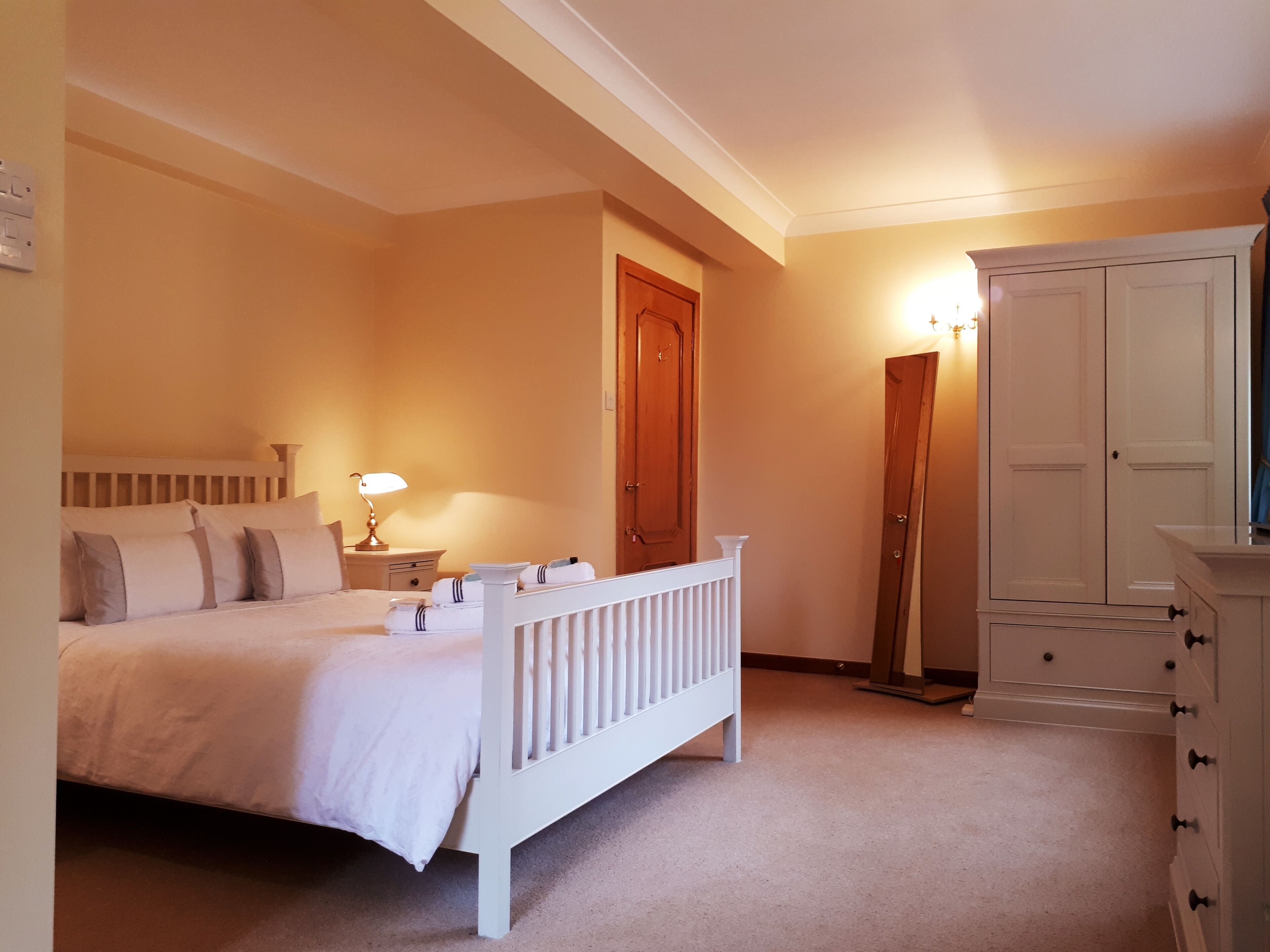 Un dormitorio con cama, mesita de noche, lámpara, armario y una puerta.