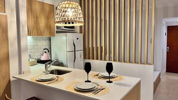 Una cocina moderna con una isla central, armarios de madera, microondas integrado y un refrigerador.