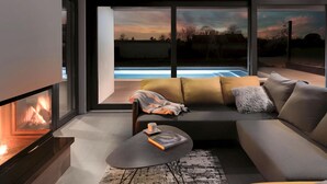Ein modernes Wohnzimmer mit Kamin, einer Couch, einem Couchtisch und Blick auf einen Swimmingpool.