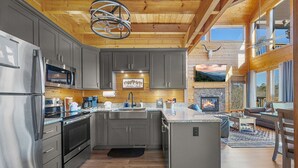 A modern kitchen with grey cabinets, stainless steel appliances, and a central island. - 20-Mile View, Hot Tub, Game Room, Waterfall (Sevierville)
