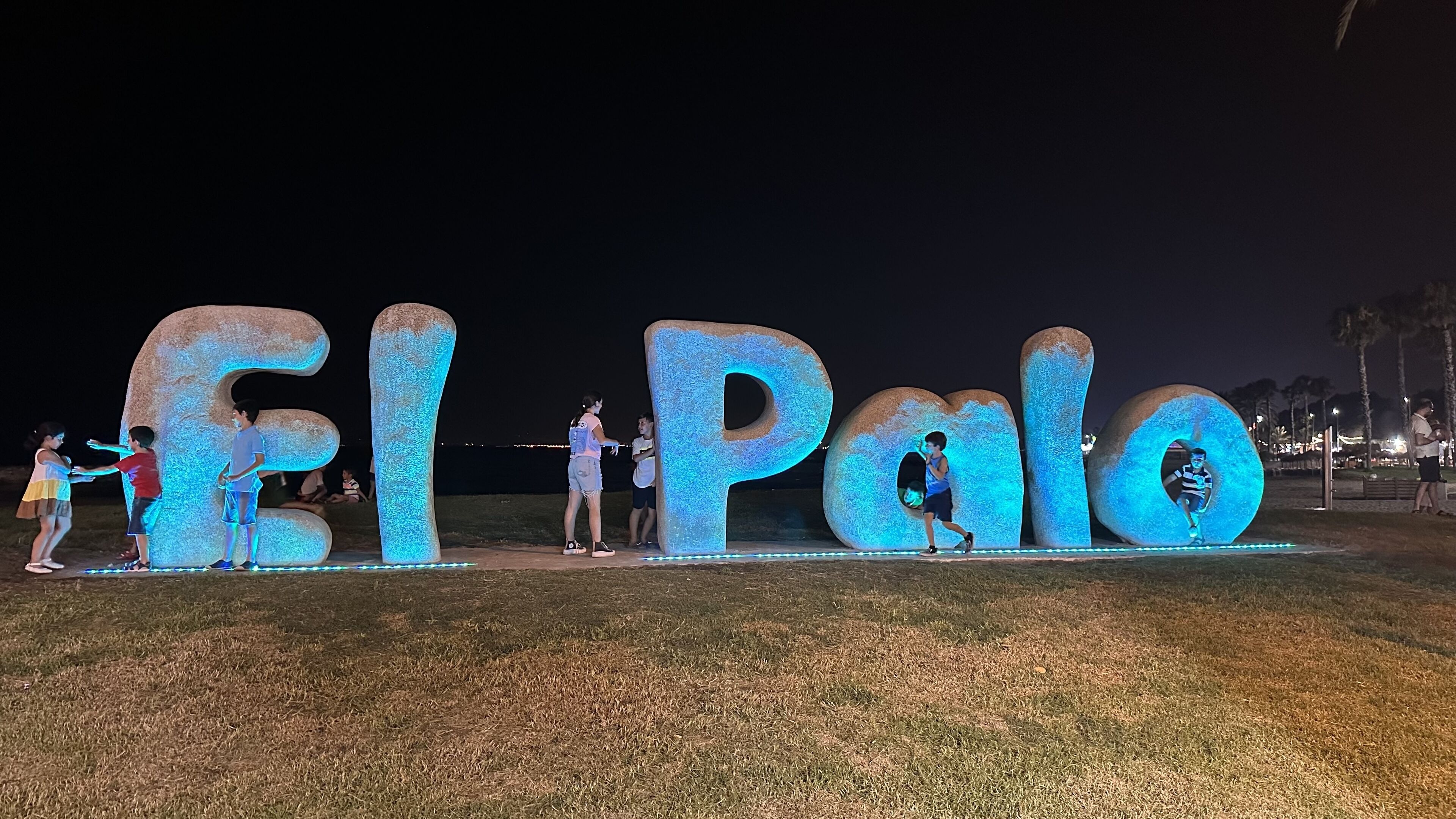 Illuminated letters spelling "El Palo" in a park at night.