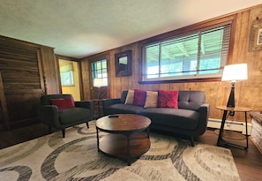 A cozy living room with a sofa, armchairs, a coffee table, and a lamp.