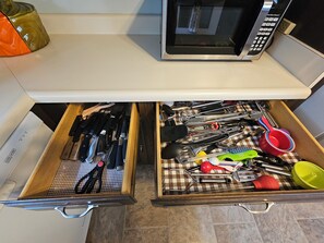 A kitchen drawer with various utensils and a microwave above it. - Private, 6-Acre Cottage with Old-Time Fishing Hole! (Friedens)
